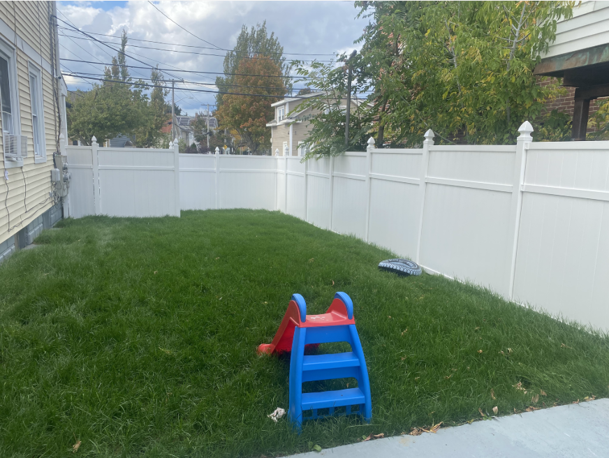 a grassy area enclosed by a white vinyl fence